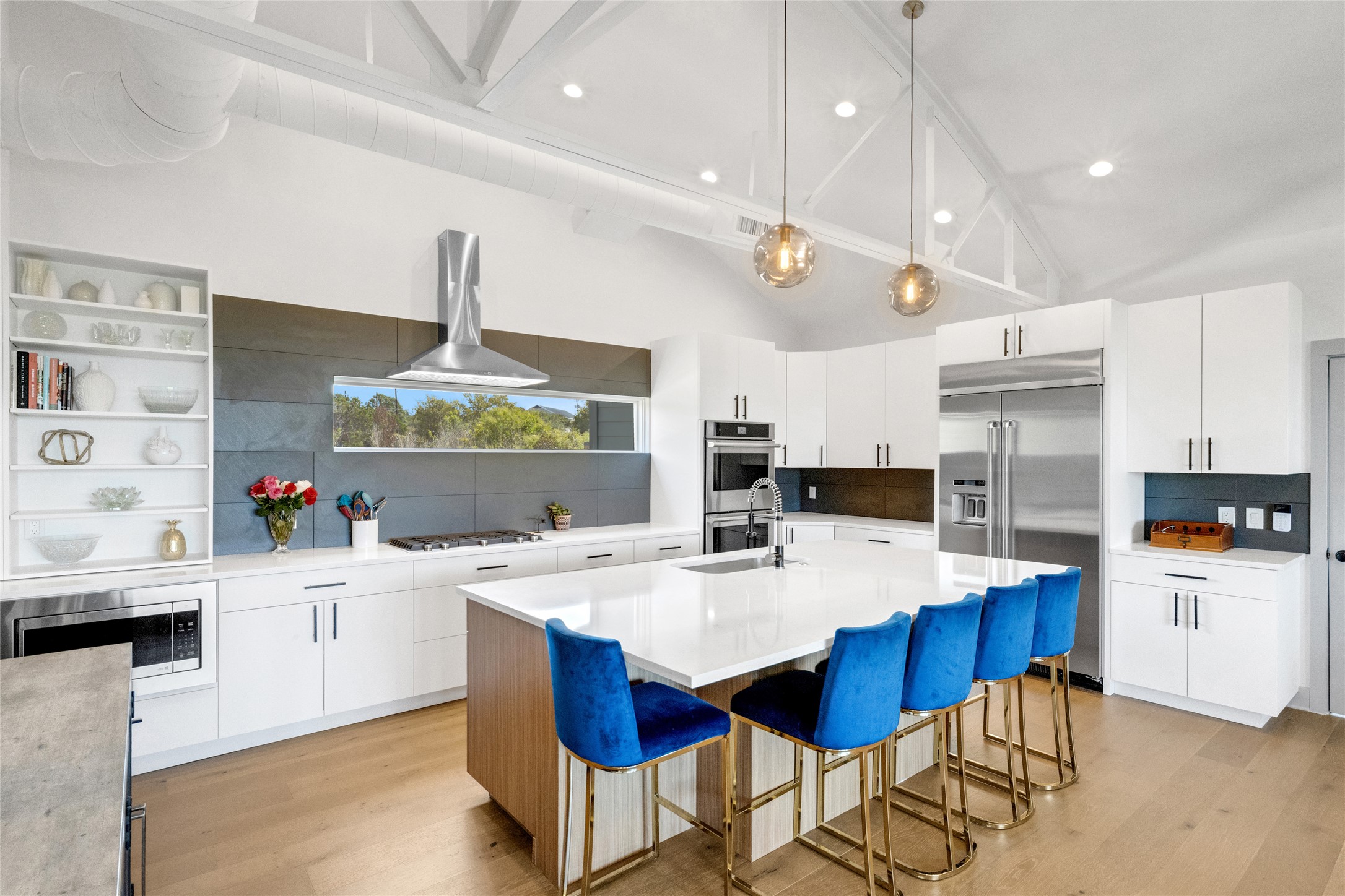 4227 Eck Lane Austin, TX 78734 - Photo 4 of 30 Kitchen featuring white cabinetry, vaulted ceiling, a breakfast bar area, built in appliances, and exhaust hood