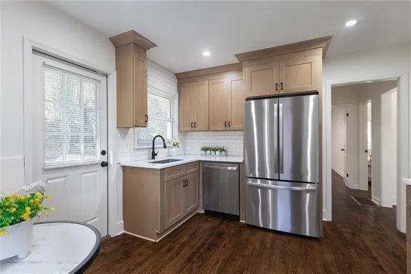 a kitchen with stainless steel appliances a refrigerator sink and wooden floor