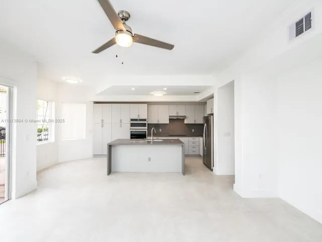 a living room with stainless steel appliances kitchen island granite countertop a stove and white cabinets