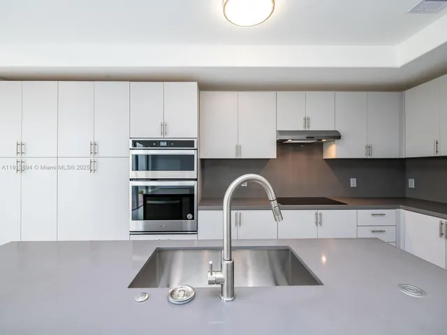 a kitchen with stainless steel appliances white cabinets and a refrigerator