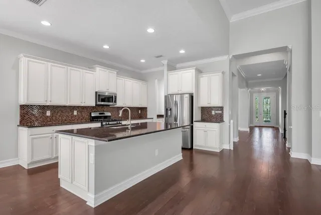 a kitchen with stainless steel appliances kitchen island granite countertop a stove and white cabinets