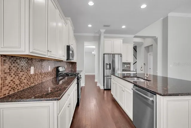 a kitchen with stainless steel appliances granite countertop a sink stove and refrigerator