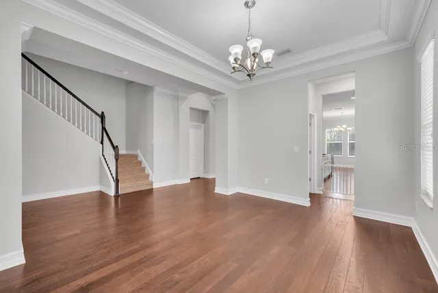 a view of an empty room with wooden floor and staircase