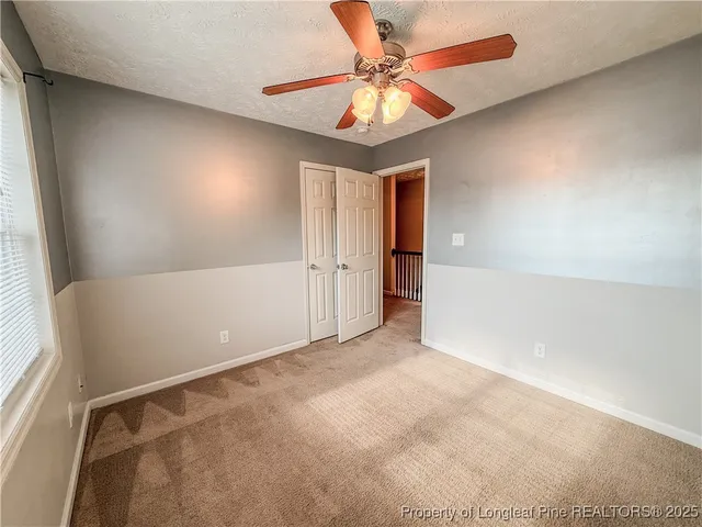 en empty room with windows and chandelier fan