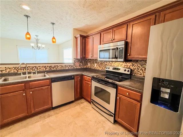 a kitchen with stainless steel appliances granite countertop a sink a stove and a refrigerator with wooden floor