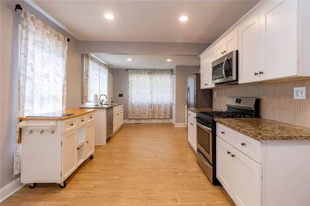 a large kitchen with stainless steel appliances granite countertop a large stove a sink and dishwasher with white cabinets