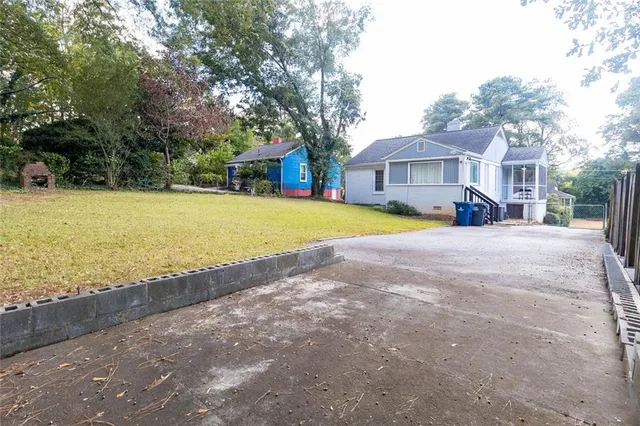 a view of a house with a yard and large trees