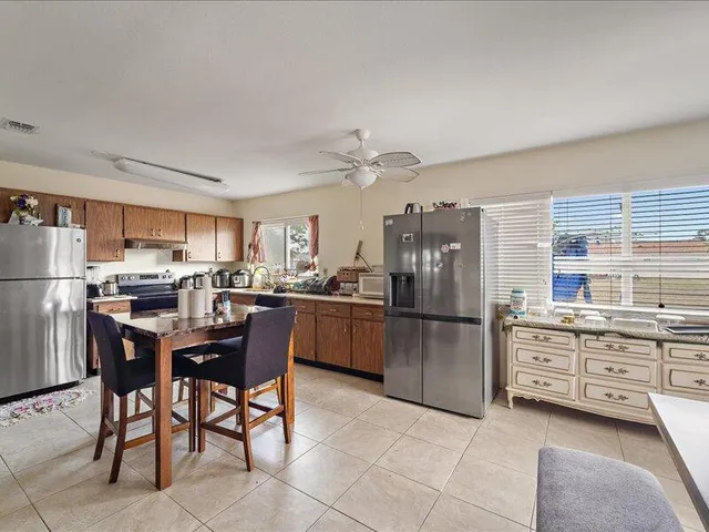 a kitchen with a refrigerator a stove a sink a dining table and chairs