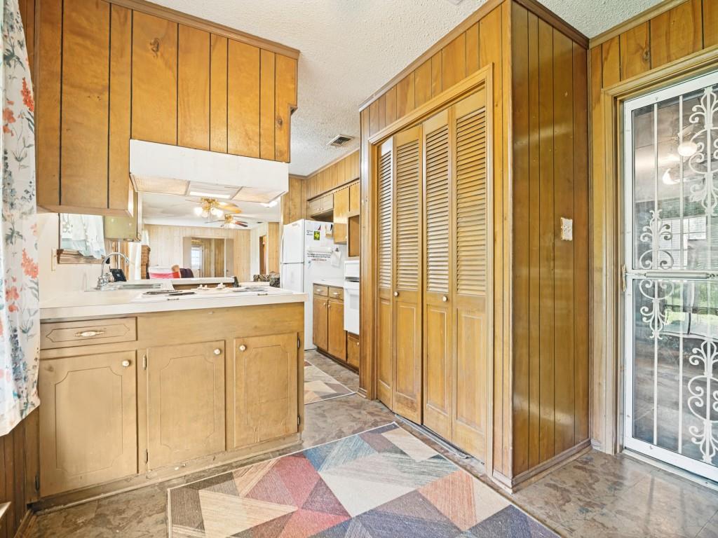 1081 Wright Street Terrell, TX 75160 - Photo 13 of 29 Kitchen featuring wood paneling, wood-finish cabinetry, light countertops, and an exterior glass door with decorative metalwork