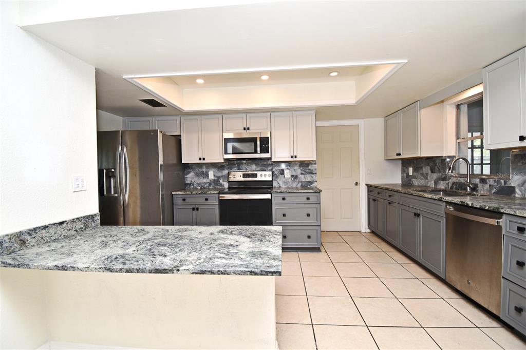 5133 Brenda Drive Orlando, FL 32812 - Photo 22 of 51 a kitchen with stainless steel appliances granite countertop a stove top oven a sink a counter top space and cabinets