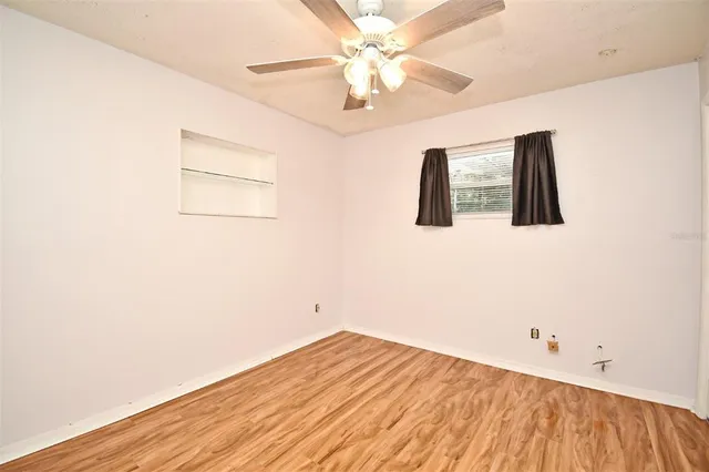 a view of a bedroom with wooden floor and a ceiling fan