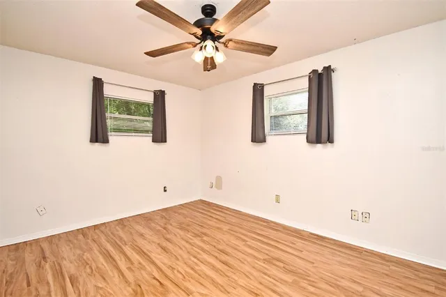 a view of a big room with wooden floor and a chandelier fan