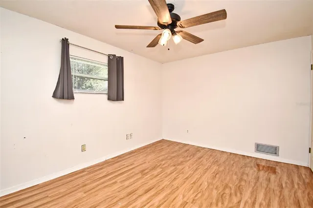 a view of a room with wooden floor and ceiling fan