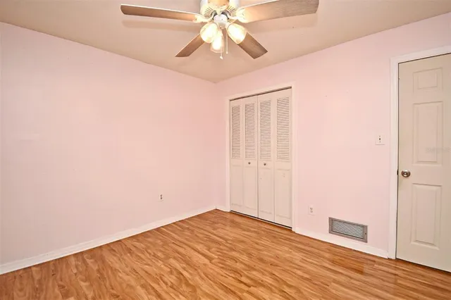 a view of empty room with wooden floor and fan