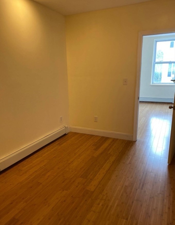 212 Maverick Street, Unit 3 Boston, MA 02128 - Photo 6 of 9 an empty room with wooden floor and windows