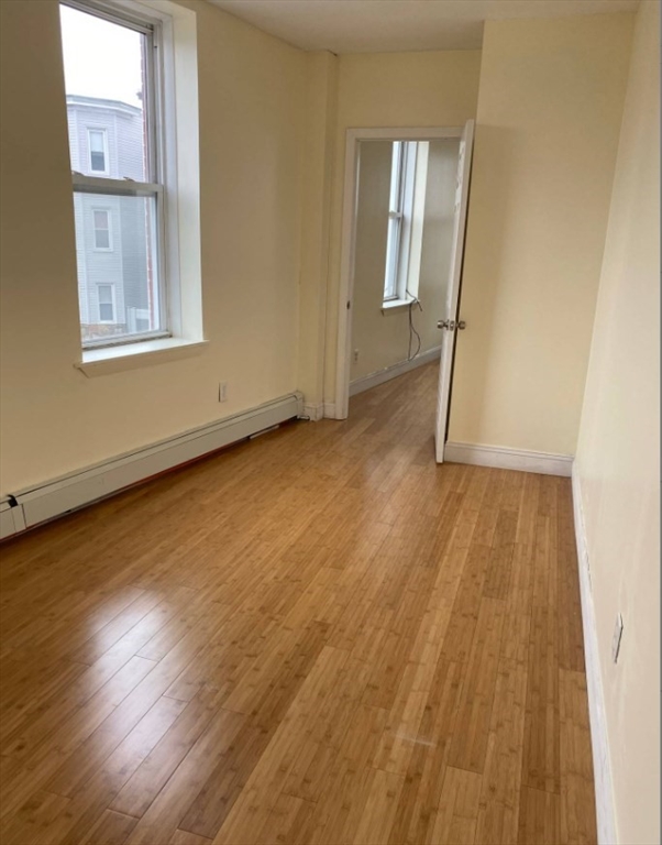 212 Maverick Street, Unit 3 Boston, MA 02128 - Photo 7 of 9 an empty room with wooden floor and windows
