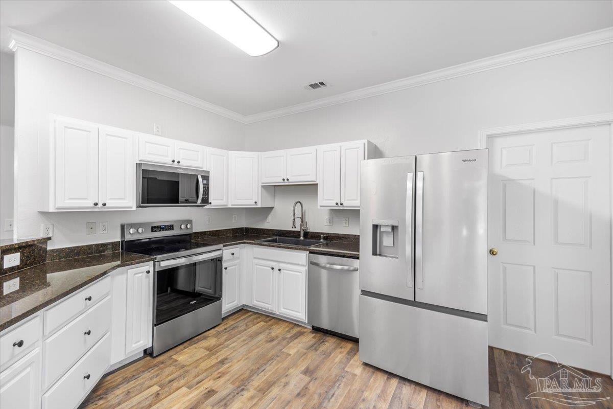 2099 Garcon Point Road Milton, FL 32583 - Photo 26 of 65 a kitchen with cabinets stainless steel appliances and wooden floor