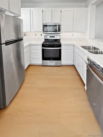 a kitchen with granite countertop a refrigerator stove and white cabinets