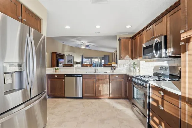 a kitchen with stainless steel appliances granite countertop a dining table chairs and a refrigerator