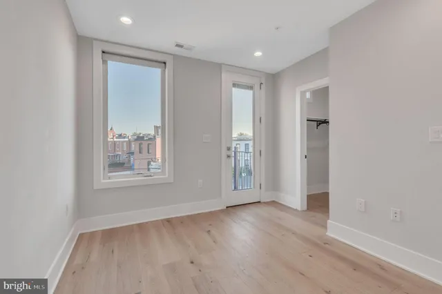 an empty room with wooden floor and windows