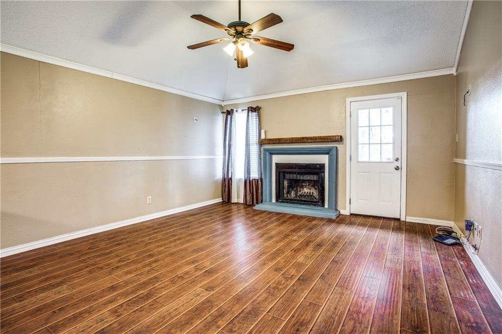 6817 Haltom Road Fort Worth, TX 76137 - Photo 22 of 25 Spacious room featuring wood-finish flooring, a fireplace with a wood mantle, and a ceiling fan