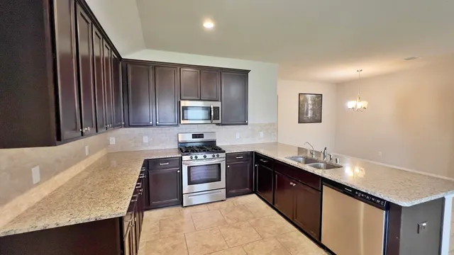 a kitchen with stainless steel appliances granite countertop a sink stove and refrigerator