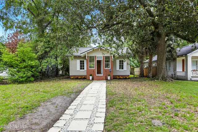 a front view of a house with a garden and trees