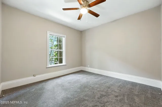 an empty room with a window and a fan