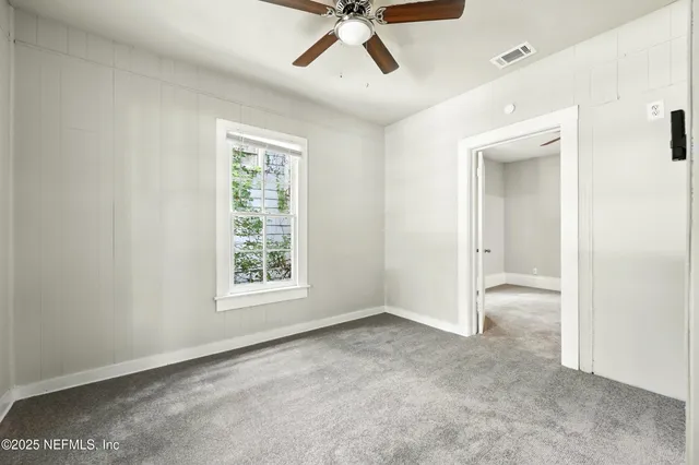 a view of a big room with windows and chandelier fan