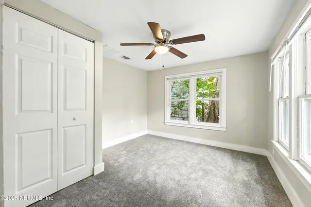 a view of empty room with window and ceiling fan