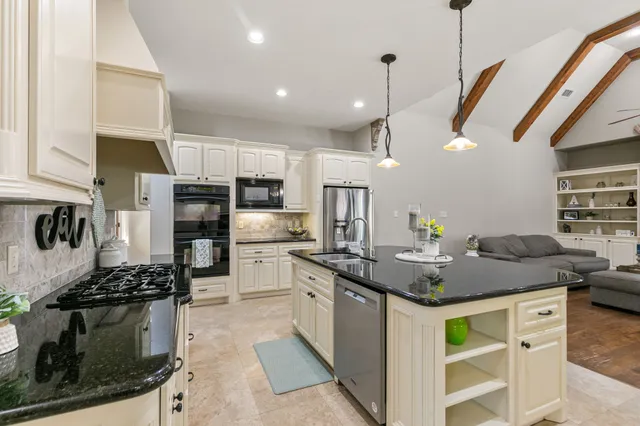 a kitchen with stainless steel appliances kitchen island granite countertop a stove a sink and a refrigerator