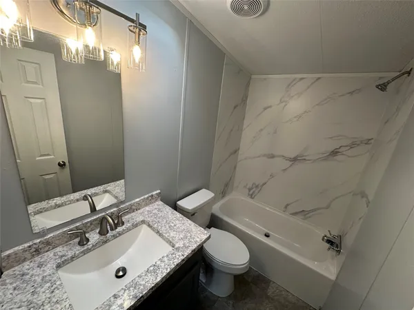 a bathroom with a granite countertop sink toilet and shower