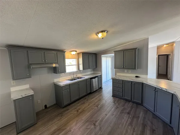a large kitchen with a wooden floor and large stainless steel appliances
