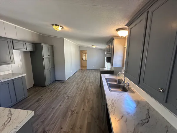 a living room with stainless steel appliances furniture a refrigerator and wooden floor