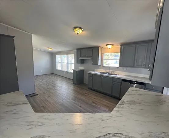a kitchen with stainless steel appliances granite countertop a sink dishwasher a stove a refrigerator a microwave oven with cabinets and wooden floor