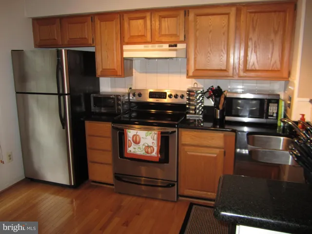 a kitchen with stainless steel appliances granite countertop a refrigerator and a stove top oven