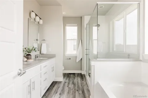 a bathroom with a double vanity sink a mirror a bathtub and next to a window