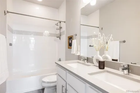 a bathroom with a double vanity sink toilet mirror and shower