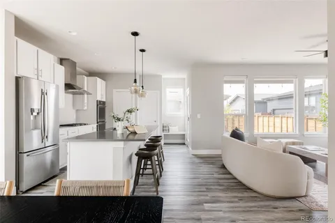 a kitchen with stainless steel appliances granite countertop a refrigerator a stove a sink dishwasher and a dining table with wooden floor