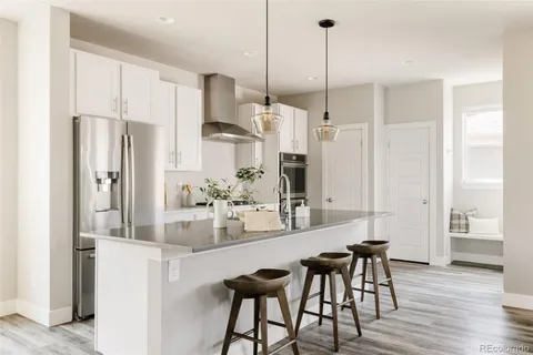 a kitchen with stainless steel appliances kitchen island granite countertop a refrigerator a sink and white cabinets
