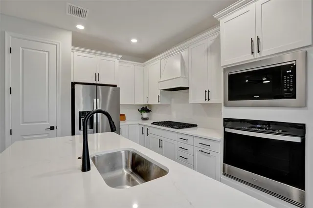 a kitchen with stainless steel appliances a stove a refrigerator a table and chairs