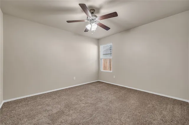 an empty room with ceiling fan and window