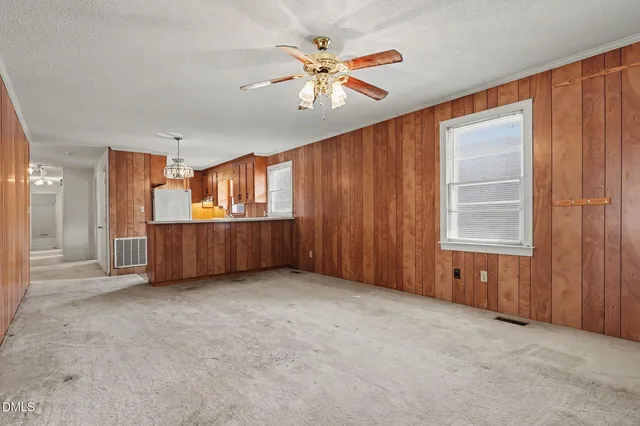an empty room with chandelier fan and windows