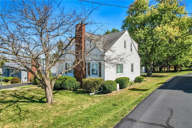 a front view of a house with garden and trees
