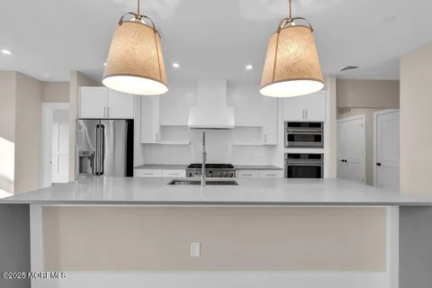 a kitchen with stainless steel appliances granite countertop a sink a stove a refrigerator and a wooden floors