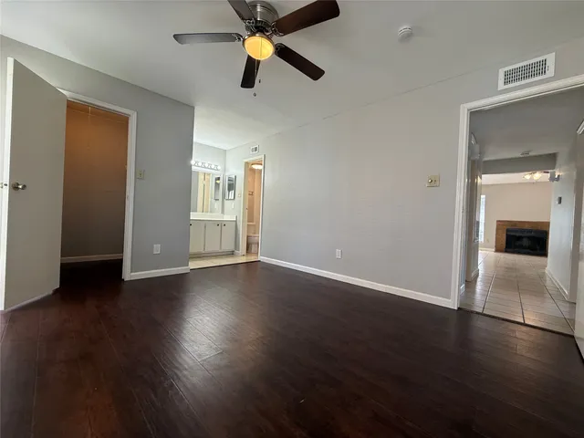 an empty room with wooden floor cabinet and windows
