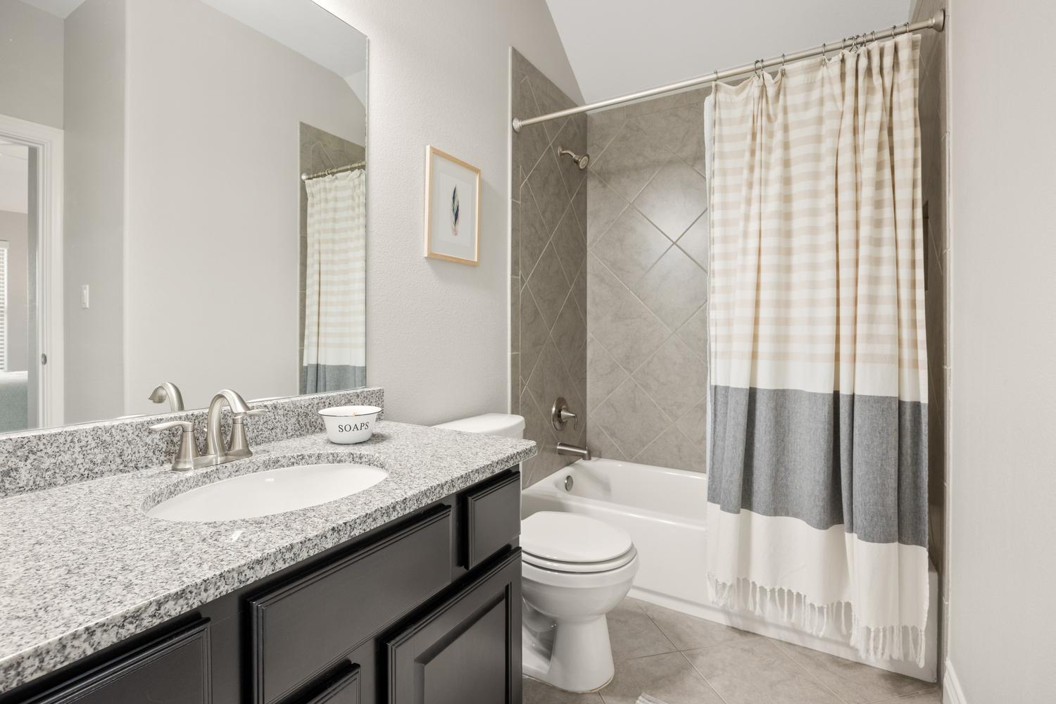 1135 Blue Ridge Drive Dripping Springs, TX 78620 - Photo 23 of 36 Modern full bathroom features a tiled shower/tub combination and a single vanity with granite countertops.