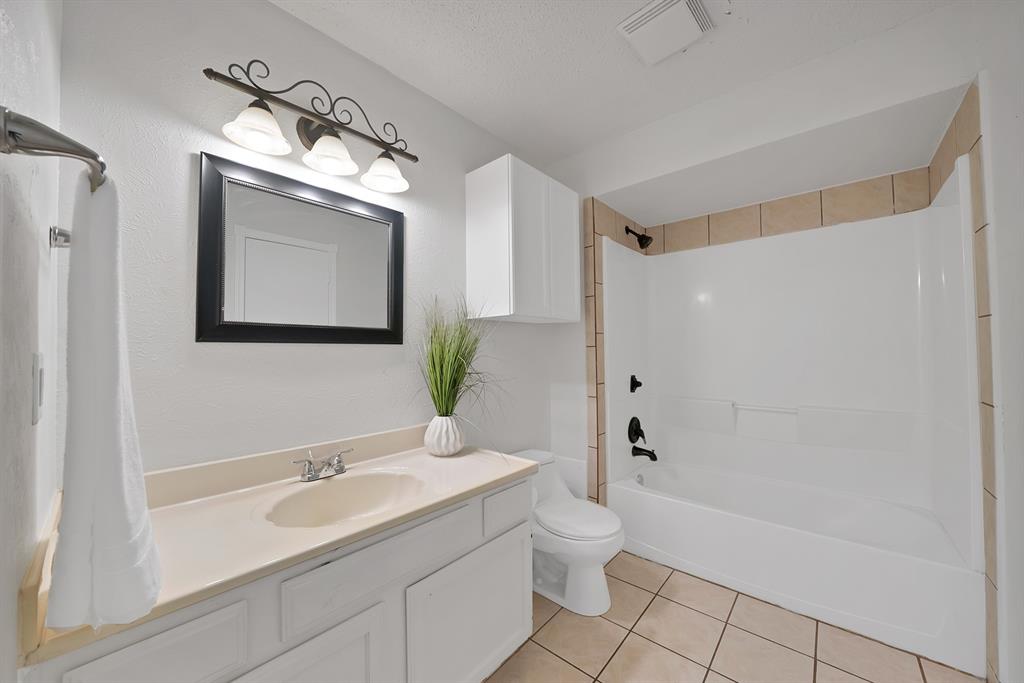 413 Wild Oak Lane Euless, TX 76039 - Photo 21 of 29 a bathroom with a toilet a sink a mirror a bathtub and shower