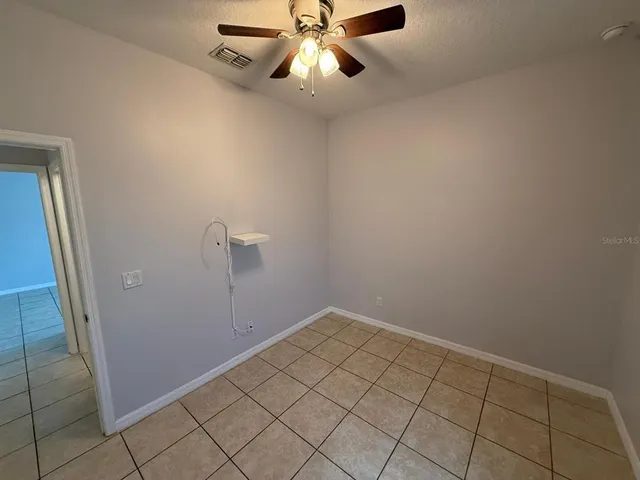an empty room with a chandelier fan and windows