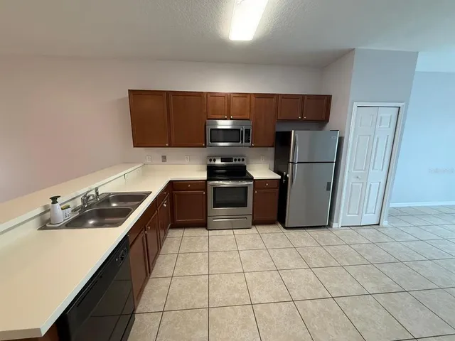 a kitchen with granite countertop a sink a stove top oven and refrigerator